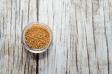 Top view of mustard in a bowl on a wooden table. Mustard located on the table. The concept of using seasonings for dishes. Eating spiced dishes.