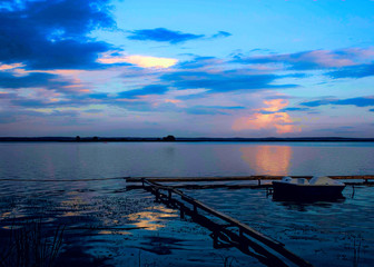 Deep blue beautiful sunset on lake with catamarans near the pier