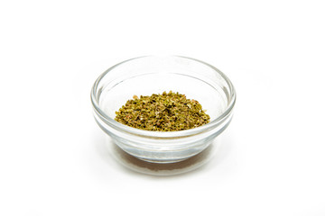 Dried oregano on a white background in a bowl. Oregano located on the table. The concept of using seasonings for dishes. Eating spiced dishes.