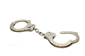 Handcuffs on an isolated white background. There are metal handcuffs on the table, the concept of handcuffing criminals. Prevention of crimes, police effectiveness.