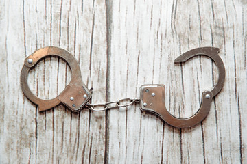 Handcuffs on a wooden background. There are metal handcuffs on the table, the concept of...