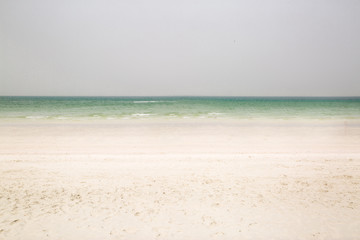 Fototapeta na wymiar White sand beach and green ocean. Space for text, copy space. Vacation concept. 