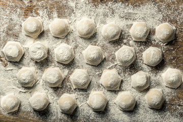 Uzbek national food Chuchvara, like dumplings, on a wooden board, in flour