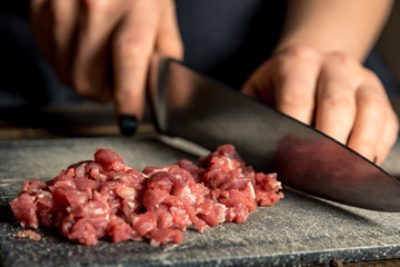 chef hands cut red meat on a board
