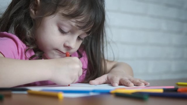 Portrait of a child painting. Cute little girl draws with wax crayons.
