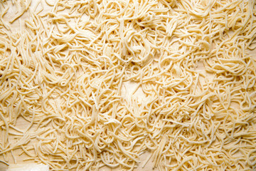 Top view on pasta noodles. The pasta lies on a wooden countertop, ready for cooking. The concept of preparing pasta.