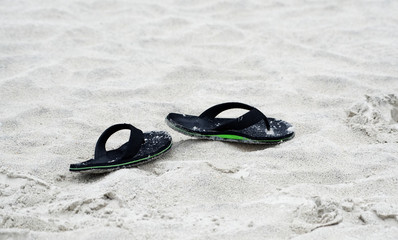 Flip-flops discarded on a sandy beach.