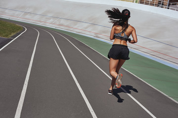 Fototapeta na wymiar Train your body. Runner on the stadium track. Woman summer fitness workout. Jogging, sport, healthy active lifestyle concept
