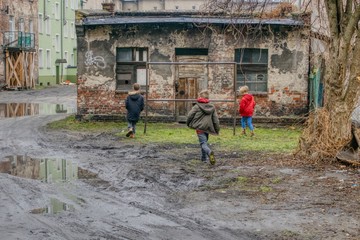 dzieci na starym zabłoconym podwórku, stara zniszczona szopa, zabawy i biegi dzieci na starym podwórku © Jarek Witkowski