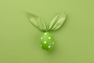 Green dotted Easter egg with paper bunny ears, holiday concept