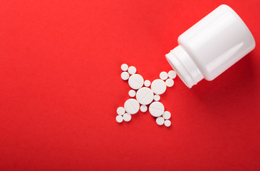 Assorted pharmaceutical medicine pills, tablets and capsules. Red background.