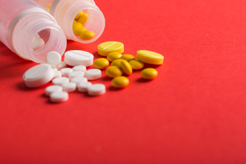 Assorted pharmaceutical medicine pills, tablets and capsules. Red background.