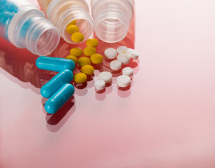 Assorted pharmaceutical medicine pills, tablets and capsules. Red background.