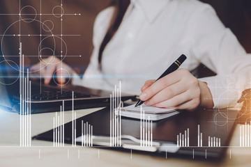 A woman working on a project in loft office. Woman develops marketing plan. Statistic graph overlay, icon innovation interface.Laptop and paperwork on the table.