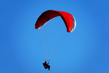 Red paraglider in a blue sky
