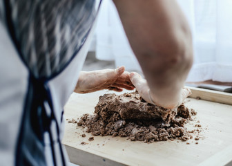 Crushing the dough. Preparing the dough by a woman. A woman kneading dough and baking cookies and gingerbreads. Grandma, my mother prepares a delicious cake for the family. Family atmosphere.