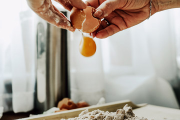 A woman smashes an egg, uses a yolk. Punching eggs for cake preparation. Concept of baking and preparing a cake for baking. Adding eggs as an ingredient to the dough. Baking gingerbreads.