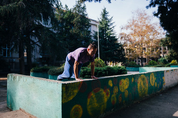 Athletic Parkour guy doing backflip and tricks while jumping off and over .a concrete wall.