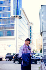 Businessman is standing in the city center near the cafe and looking interested in his notebook.