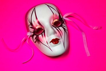 white Mardi Gras mask pink background