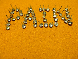 Word pain put together out of small up side down nails at the yellow cork pin board