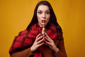 Beautiful brunette woman with big red knitted scarf drinking a hot tea