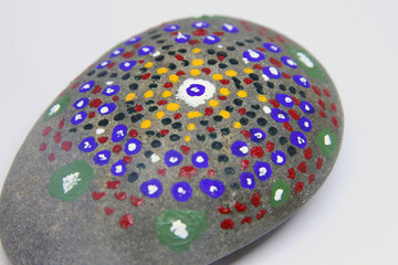 closeup of a uniquely painted grey stone on white background