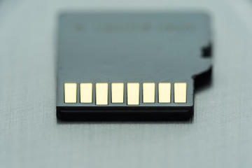 black micro sd card with gold contacts on a gray metallic surface