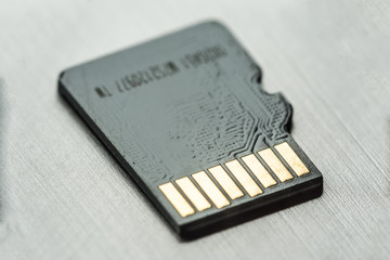 black micro sd card with gold contacts on a gray metallic surface