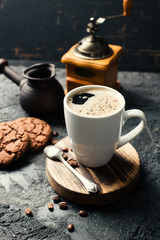 Black fried coffee beans in cafe with cookie and cake on dark textured background
