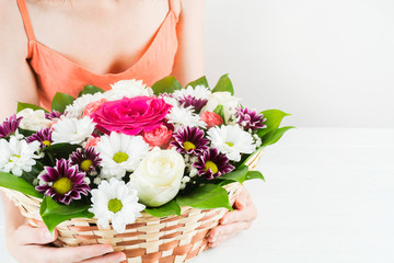 Wicker basket with bouquet of flowers in woman hands