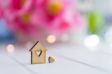 Obraz na płótnie Canvas Closeup wooden house with hole in form of heart with beautiful bouquet of tender pink tulips on blurred background with bokeh.