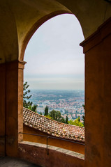 A large window through which is visible the panorama of the city of Bologna