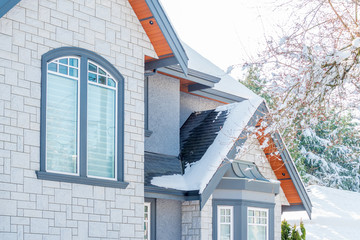 A perfect neighbourhood. Houses in suburb at Winter in the north America. Fragment of a luxury house covered nice snow.