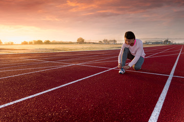 Pretty young girl doing sports on running tracks with pink cap and sweatshirt