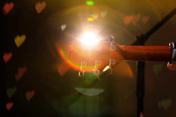 Guitar headstock on concert stage background with hearts light flare effect. Back view of guitar headstock during spectacle. Best conceptual picture for concerts, spectacles or show banners.