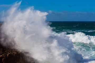 Sea waves hitting rocks cliff at Praia Da Bordeira, Portugal