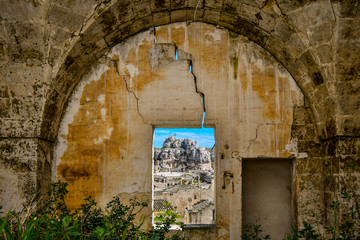Fototapeta na wymiar View through a window in a medieval, cracked stone wall of the ancient Madonna de Idris rock church and the Sassi of Matera, Italy, in the Basilicata region.