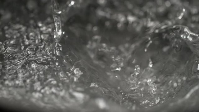 SLOW MOTION, MACRO, DOF: A piece of ice falls into a pot of boiling water. Ice cubes are dropped into a boiling viscose and transparent liquid. Hot vinegar splashing after ice cubes fall into the pan.
