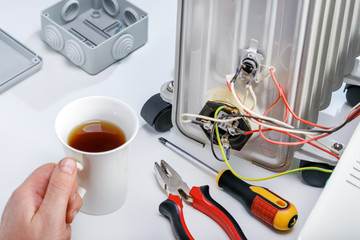 Hand of man holding cup with tea on the workplace. Break time. Repair concept.