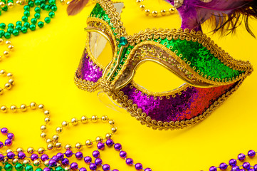 Fat Tuesday traditional accessory and Mardi Gras carnival concept theme with close up on a face mask full of color, feathers and texture and colorful beads, a staple of the festival in New Orleans