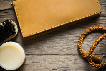 Vintage genuine leather wallet on wooden table prepare to clean and care with wax. maintenance concept. Men accessories on rustic wood.