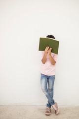 Cute asian little girl and stack of books  while standing on floor white wall background ,back to school concept