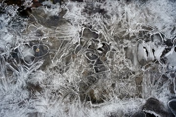 Cracked ice on shallow water with stones inside