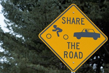 Sign share the road with green tree and blue sky behind