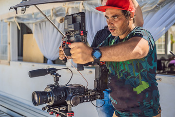 the production team on a commercial video shoot. Steadicam operator uses the 3-axis camera...
