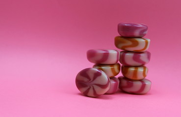 sweet candies caramel on a pink background stacked on top of each other