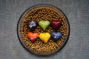 Six colorful chocolate heart candies on milk chocolate pearls
