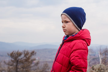 Portrait of a boy in a red jacket on the sky background