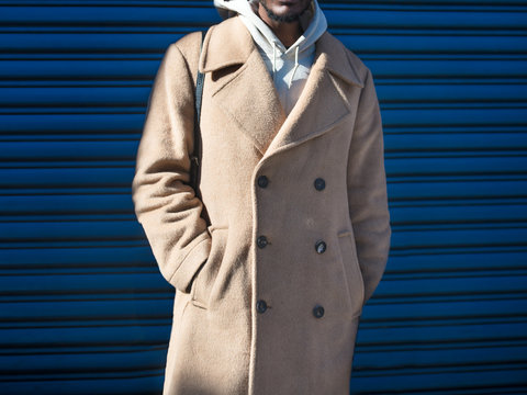 Men`s beige cashmere wool jacket on male model posing near blue wall in the city street